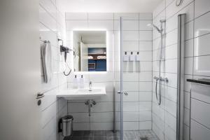 ein weißes Badezimmer mit Waschbecken und Dusche in der Unterkunft Scandic Glostrup in Glostrup