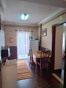 une cuisine avec une table, des chaises et un réfrigérateur dans l'établissement Guesthouse, Ap Veríssimo, à Nazaré