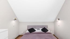 a white bedroom with a bed with black pillows at Apartament pod Bukiem in Ostrzyce +14 photos