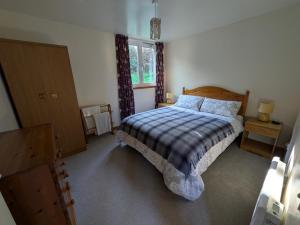 ein Schlafzimmer mit einem Bett und einem Fenster in der Unterkunft Strathpeffer Holiday Cottages in Strathpeffer