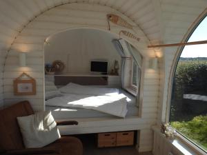 a bed in a small room with a window at Tiny House De Boet, in Natuurgebied en vlakbij het Strand in Callantsoog