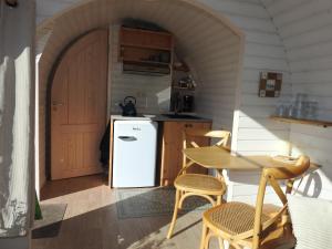 a small kitchen with a table and a refrigerator at Tiny House De Boet, in Natuurgebied en vlakbij het Strand in Callantsoog