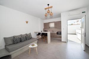 a living room with a gray couch and a kitchen at Litmus in Fira