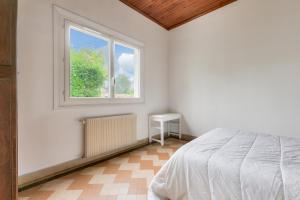 een witte slaapkamer met een bed en een raam bij Maison de vacances familiale proche de la plage in Andernos-les-Bains