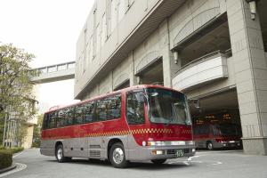 a red bus driving down a street next to a tall building at Imperial Hotel Osaka in Osaka