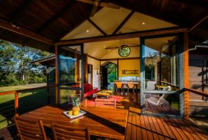 a conservatory of a house with a wooden table and chairs at Promised Land Retreat in Bellingen