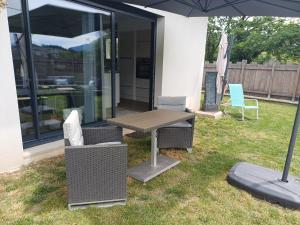 a patio with a table and chairs and an umbrella at Maison cosy in Grésy-sur-Aix