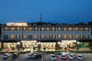 a large building with cars parked in a parking lot at Keptur Hotel in Dosemealti