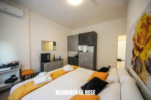 a bedroom with a large white bed with a couch at Residenza Le Rose in Peschiera del Garda