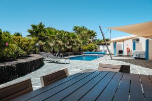 a wooden table and chairs next to a swimming pool at CASA FATIMA Villa with heated pool and jacuzzi in Lajares