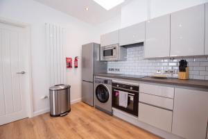 a kitchen with white cabinets and a washer and dryer at Affleck Retreat 5 - SJA Stays - Modern 1 Bed Apartment in Aberdeen