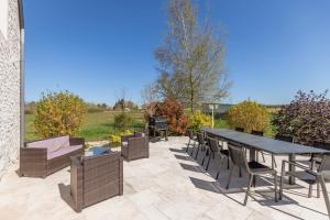 a patio with a table and chairs on a patio at La Longère de l'Éolienne - Clim, billard & jardin in Billy