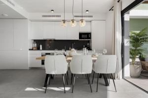 a kitchen with a dining table and white chairs at VIVI Homes - Bonita del Sol Beach, Pool, Garden, GYM & SPA in La Cala de Mijas
