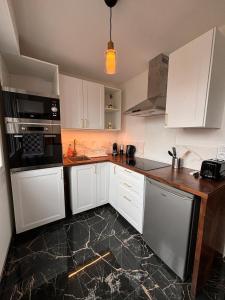 a kitchen with white cabinets and a black counter top at LE GOLDEN accès direct tramway Genève avec parking in Ambilly