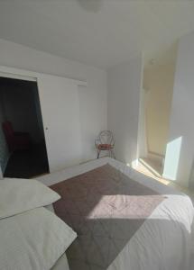 a white bedroom with a bed and a chair at La Golondrina in Villefranche-sur-Saône +1 photo