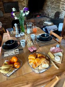 a wooden table topped with baskets of bread and fruit at Mas Soubeyran in Saint-Michel-de-Dèze