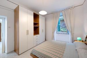 a white bedroom with a bed and a window at La Finestra sul Mare in Genoa