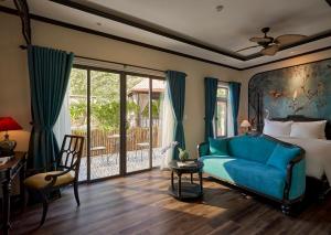 a bedroom with a blue couch and a bed and a patio at The An Bang Vanessa - Indochine Boutique Hotel in Hoi An