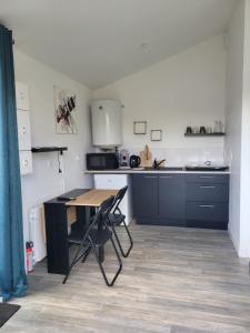 a kitchen with a wooden table and a desk at Le Studio in Saint-Pierre-Montlimart