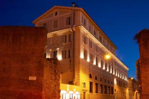 Un grand bâtiment blanc avec des lumières allumées la nuit dans l'établissement Hotel The Building, à Rome