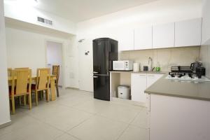 a kitchen with a black refrigerator and tables and chairs at גרדניה פריים in Eilat