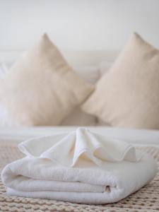 ラワイビーチにあるLeivi Villa 3 bedroomsの枕が置かれたベッドの上に白いタオルが積み重ねられている