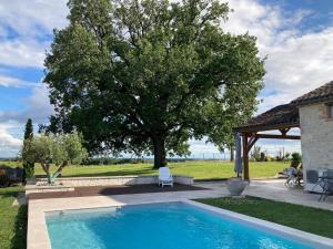 a swimming pool in a yard with a tree at La grange à Tissac in Cazes-Mondenard