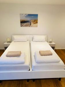 two white beds in a room with a painting on the wall at Milis Apartments in Radolfzell am Bodensee