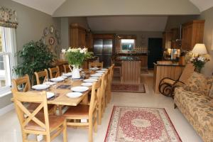 a dining room with a long table and a kitchen at Inchiquin House, period home in the heart of the Burren in Corrofin