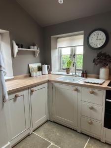 eine Küche mit Spüle und einer Uhr an der Wand in der Unterkunft Cedar Cottage newly renovated cottage in Matlock + 14 Fotos