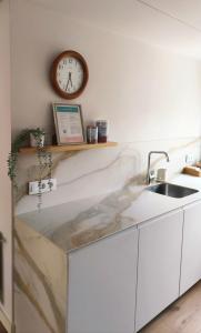 サンタンデールにあるPrecioso Apartamento Nuevo Céntrico en Santanderのシンクと壁に時計が付いたキッチン