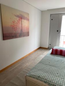 a bedroom with a bed and a painting on the wall at Apartamento Duplex - Beach Apart in Vila Praia de Âncora
