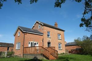 ein altes Backsteinhaus mit einer Holzterrasse davor in der Unterkunft Prince Rupert's cottage with garden in Sibbertoft