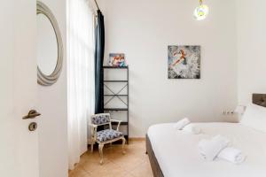 een slaapkamer met een bed, een spiegel en een stoel bij Neoclassical Loft in Monastiraki - Acropolis and metro in Athene
