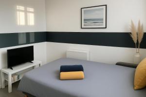 a bedroom with a bed and a television at Studette Sable & Mer cosy à 100m de la plage in Merville-Franceville-Plage