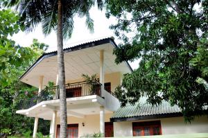 a house with a balcony and two palm trees at Anuradha Holiday Apartments in Anuradhapura