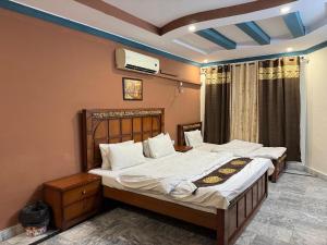 a bedroom with two beds and a tv on the wall at Lexus Lodge in Islamabad