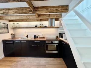 a kitchen with black cabinets and wooden ceilings at La Maison Diderot, Centre de Rennes in Rennes