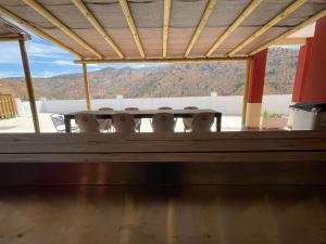 a table and chairs on a porch with mountains in the background at Casa Rural El Burro Bajo in Casabermeja