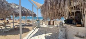 a beach with chairs and tables and straw umbrellas at 27 Via Agricola in Pozzallo