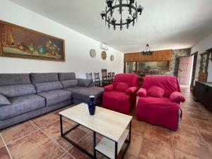 a living room with a couch and red chairs at Casa Rural El Burro Bajo in Casabermeja