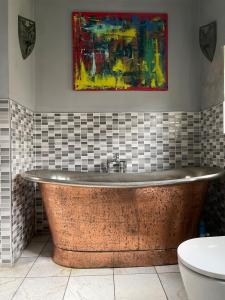 a bath tub in a bathroom with a painting on the wall at Quirky house in Manchester +21 photos