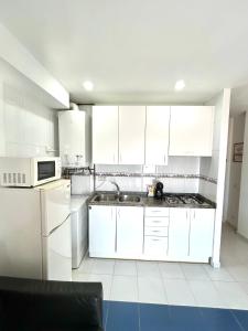 eine Küche mit weißen Schränken und einer Spüle in der Unterkunft Apartamento Zodiac AB 2 C in Lloret de Mar