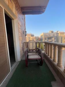 a chair sitting on a balcony with a green carpet at Baraa house in Cairo