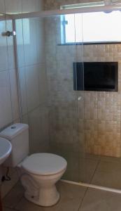 a bathroom with a toilet and a glass shower at Pousada Cedro Ilha Comprida in Ilha Comprida