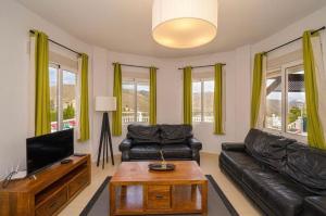 a living room with a black leather couch and a tv at Casa Violetta in Alicante