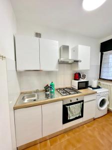 a kitchen with white cabinets and a sink at Casa Segantini - Panorama Pool Apartment in Riva del Garda