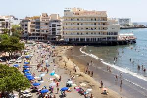 a group of people on a beach with umbrellas at Relax by the Sea at Medano Retreat Terrace Pool in El Médano