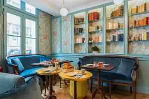 パリにあるオテル ドゥ ヌーヴ バイ ハッピーカルチャーのテーブル、椅子、本棚のあるレストラン