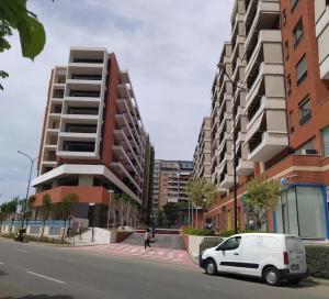 ein weißer Van auf einer Straße neben hohen Gebäuden geparkt in der Unterkunft tirana delijorgjis appartment in Tirana